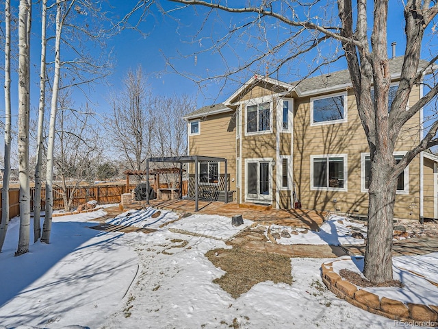 snow covered rear of property with fence and a pergola