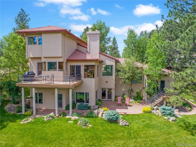 2398 Bitterroot Ln, Golden, CO 80401 - rear view of house featuring stucco siding, a chimney, a lawn, and a tile roof