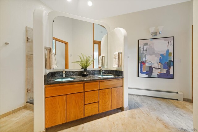 2398 Bitterroot Ln, Golden, CO 80401 - bathroom featuring baseboard heating, double vanity, a shower with shower door, and marble finish flooring
