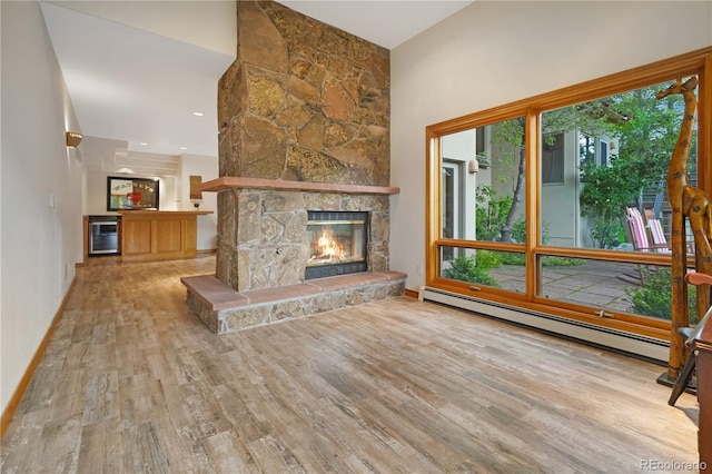 2398 Bitterroot Ln, Golden, CO 80401 - unfurnished living room featuring a baseboard radiator, wood finished floors, beverage cooler, a stone fireplace, and a towering ceiling