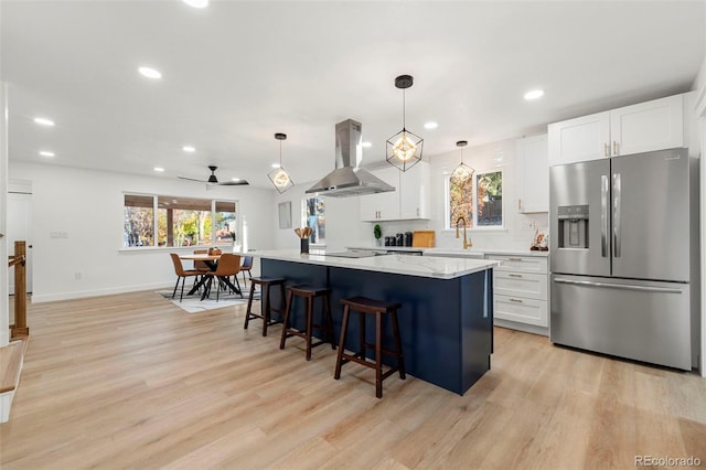 kitchen with stainless steel fridge, white cabinetry, and island range hood