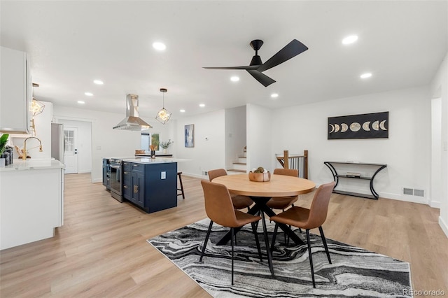 dining space featuring light hardwood / wood-style flooring, ceiling fan, and sink