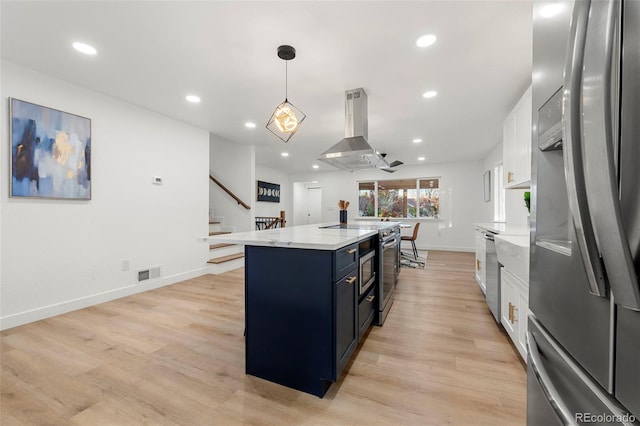 kitchen with stainless steel appliances, white cabinetry, island range hood, hanging light fixtures, and light wood-type flooring