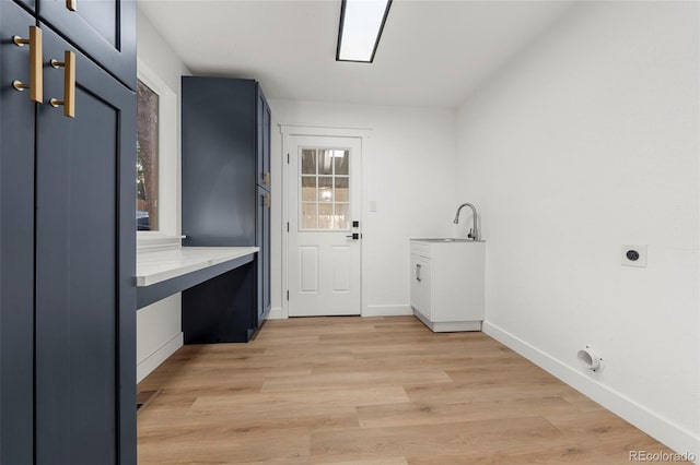 washroom with hookup for an electric dryer, light hardwood / wood-style flooring, cabinets, and sink