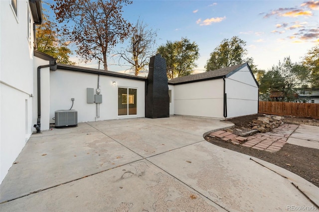 back house at dusk featuring central air condition unit and a patio area