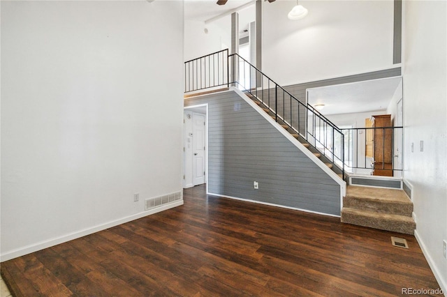 unfurnished living room with a towering ceiling and dark hardwood / wood-style floors