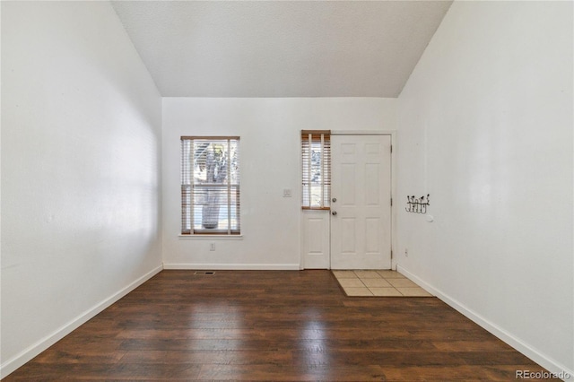 foyer featuring dark wood-type flooring and vaulted ceiling