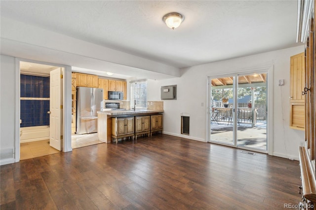 kitchen featuring dark hardwood / wood-style flooring, kitchen peninsula, stove, and stainless steel refrigerator