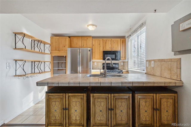 kitchen with sink, stainless steel refrigerator, light tile patterned floors, and tile counters