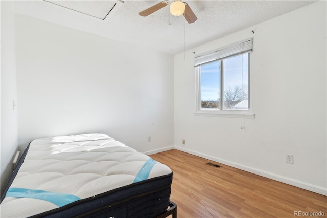 bedroom with hardwood / wood-style flooring, a textured ceiling, and ceiling fan