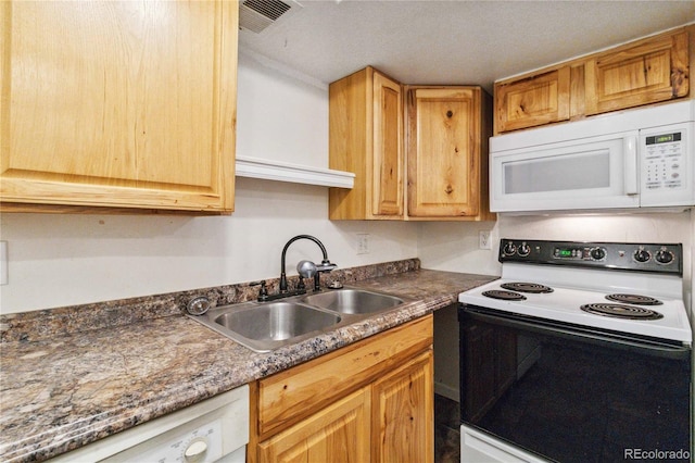 kitchen featuring sink, white appliances, and dark stone counters