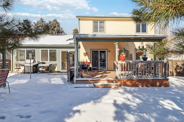 snow covered back of property featuring a deck