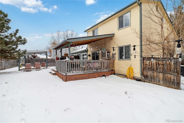 snow covered house with central air condition unit and a wooden deck