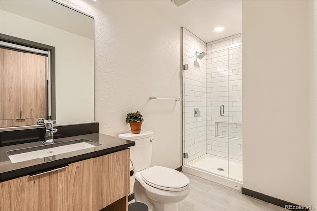 bathroom with hardwood / wood-style flooring, a shower with door, toilet, and vanity