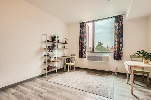 sitting room with an AC wall unit and light wood-type flooring