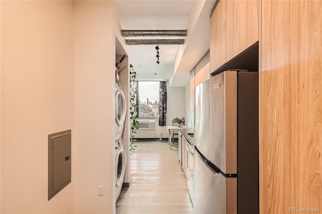 kitchen with light brown cabinetry, stacked washer and dryer, stainless steel fridge, light hardwood / wood-style flooring, and electric panel