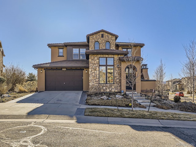 mediterranean / spanish-style house with stucco siding, an attached garage, stone siding, driveway, and a tiled roof