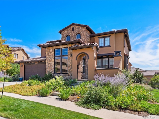 2256 S Isabell Ct, Lakewood, CO 80228 - mediterranean / spanish home featuring stucco siding, stone siding, an attached garage, fence, and a tiled roof