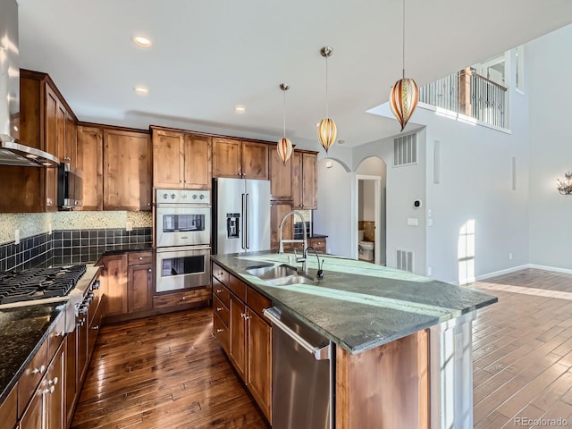 2256 S Isabell Ct, Lakewood, CO 80228 - kitchen with a sink, appliances with stainless steel finishes, wall chimney range hood, dark wood finished floors, and arched walkways