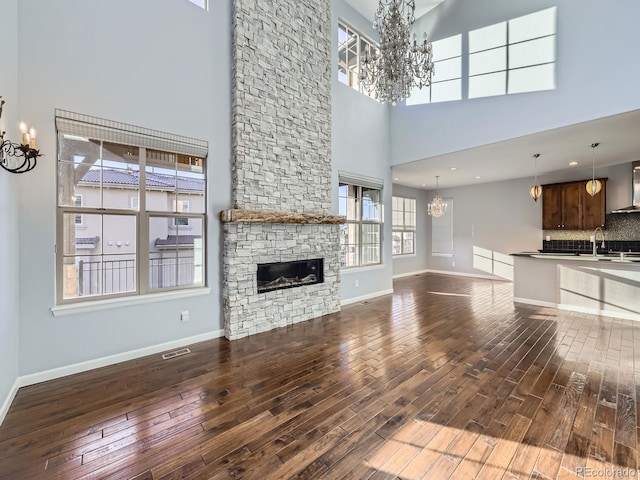 2256 S Isabell Ct, Lakewood, CO 80228 - unfurnished living room featuring a chandelier, dark wood-style floors, a high ceiling, a fireplace, and baseboards