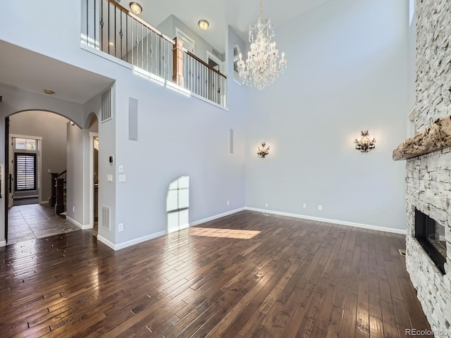 2256 S Isabell Ct, Lakewood, CO 80228 - unfurnished living room with arched walkways, a towering ceiling, dark wood-style flooring, a chandelier, and a fireplace