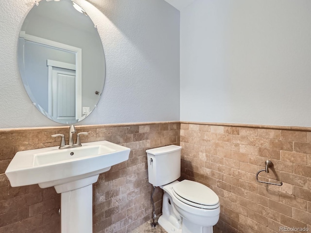 2256 S Isabell Ct, Lakewood, CO 80228 - half bathroom featuring toilet, wainscoting, tile walls, and a sink