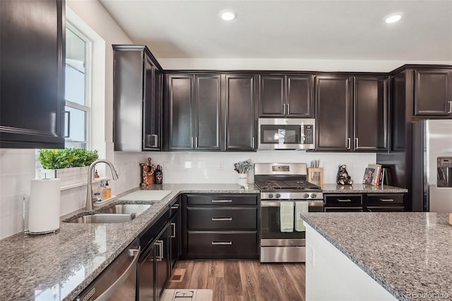 kitchen with light stone countertops, sink, stainless steel appliances, dark hardwood / wood-style floors, and dark brown cabinets