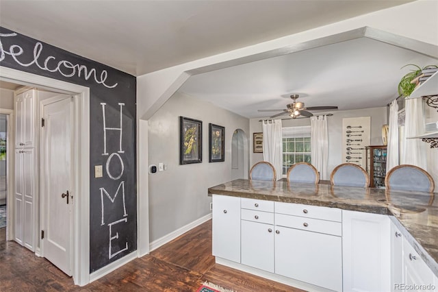 134 S 5th Ave, Brighton, CO 80601 - kitchen with a peninsula, white cabinetry, baseboards, and dark wood-type flooring