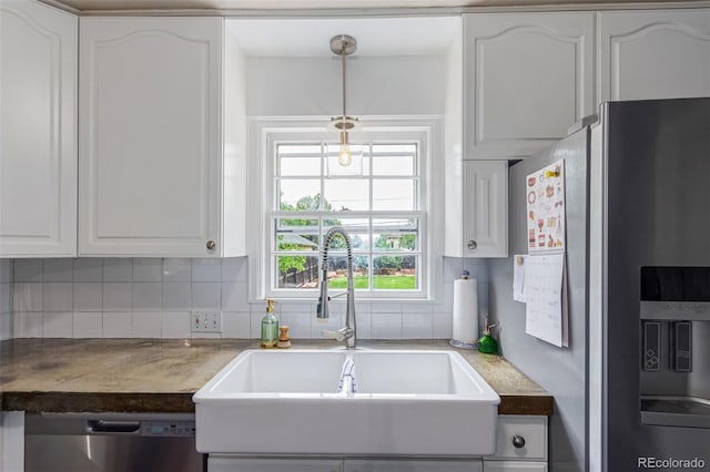 134 S 5th Ave, Brighton, CO 80601 - kitchen featuring appliances with stainless steel finishes, a sink, white cabinetry, backsplash, and hanging light fixtures