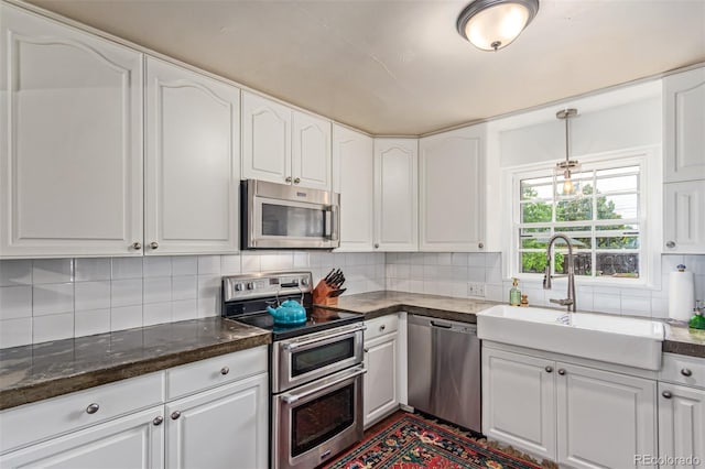 134 S 5th Ave, Brighton, CO 80601 - kitchen featuring stainless steel appliances, a sink, white cabinetry, decorative backsplash, and pendant lighting