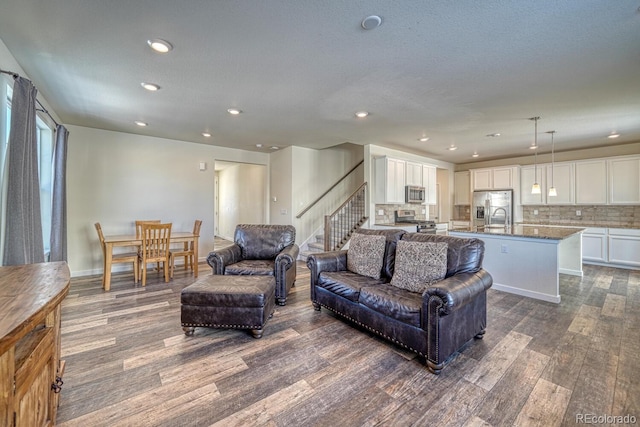 living room with dark wood-type flooring, sink, and a textured ceiling