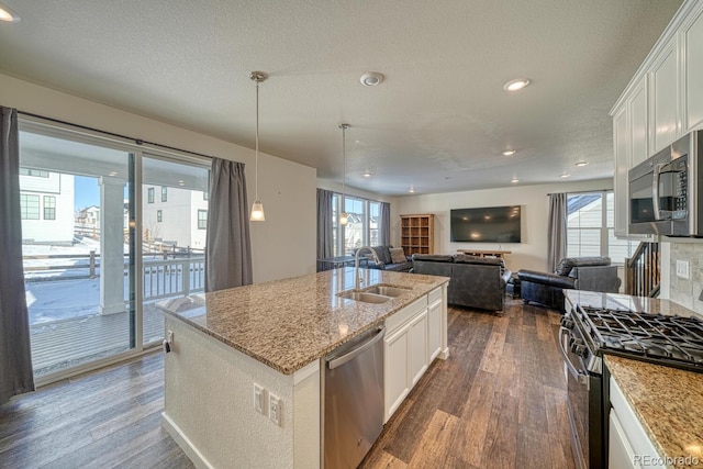 kitchen with sink, white cabinetry, a kitchen island with sink, stainless steel appliances, and light stone counters