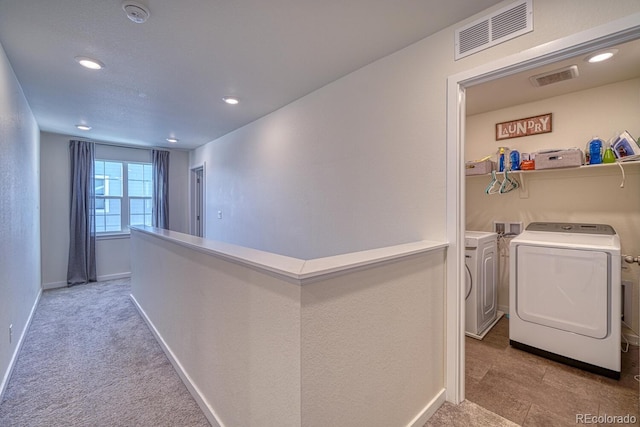 hall featuring washing machine and dryer and light colored carpet