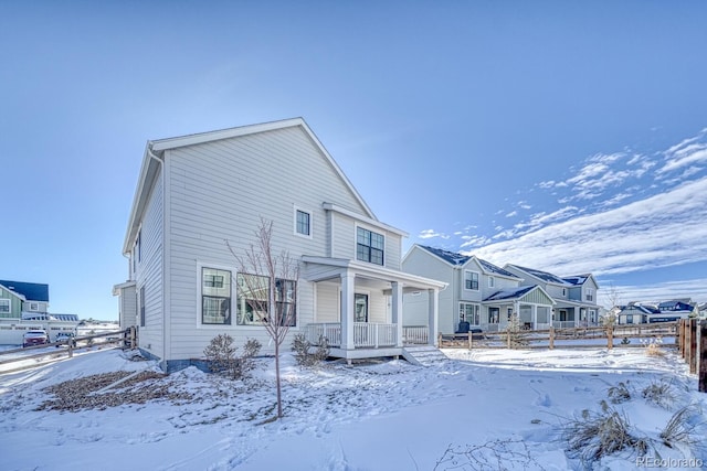 snow covered back of property with covered porch