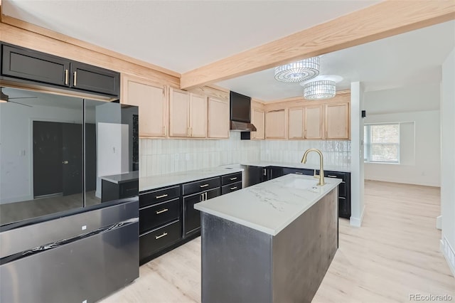 kitchen with sink, light hardwood / wood-style flooring, light brown cabinets, a kitchen island with sink, and backsplash