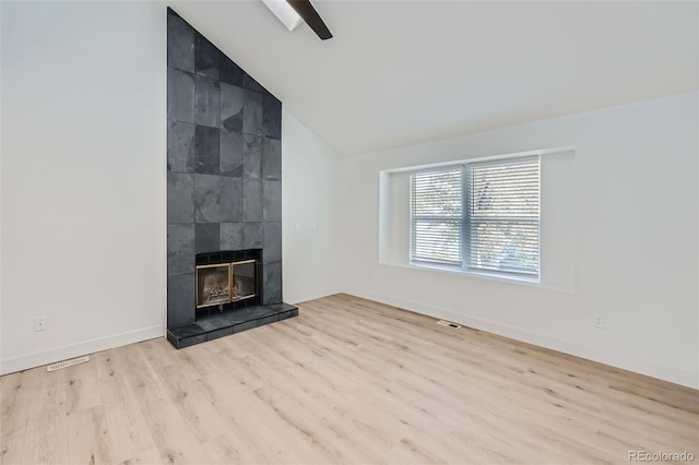 unfurnished living room with a tiled fireplace, lofted ceiling, and light hardwood / wood-style floors