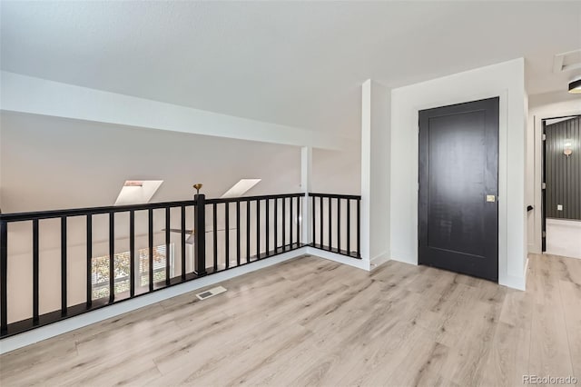 spare room featuring light hardwood / wood-style floors and a skylight