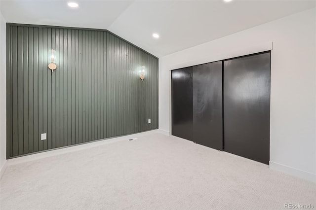 unfurnished bedroom with vaulted ceiling, a closet, and carpet flooring