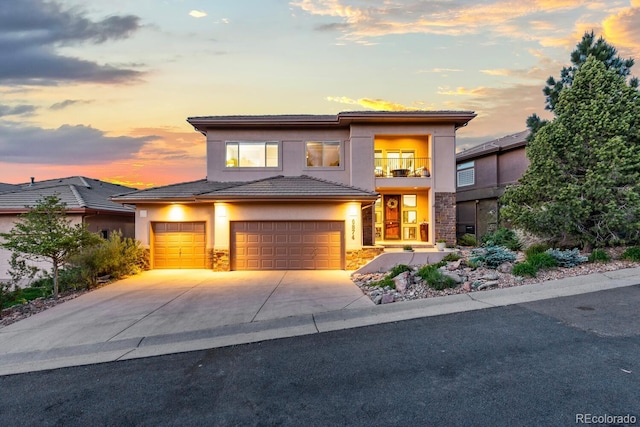 6874 Raspberry Run, Littleton, CO 80125 - view of front facade featuring a balcony, stone siding, stucco siding, driveway, and an attached garage