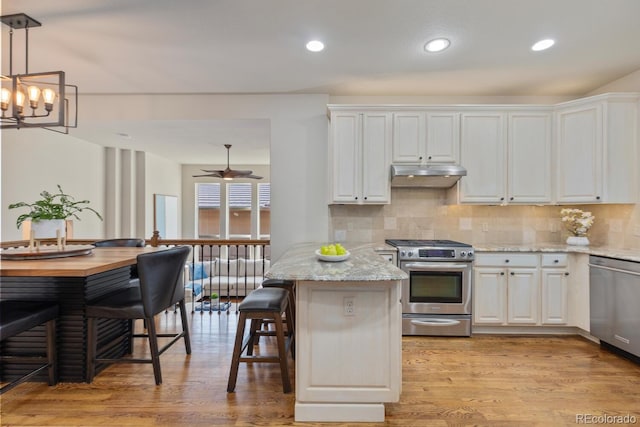 6874 Raspberry Run, Littleton, CO 80125 - kitchen featuring appliances with stainless steel finishes, under cabinet range hood, white cabinets, backsplash, and recessed lighting