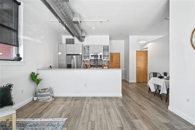 3100 Huron St Unit 1A, Denver, CO 80202 - kitchen featuring appliances with stainless steel finishes, light wood finished floors, glass insert cabinets, track lighting, and decorative backsplash