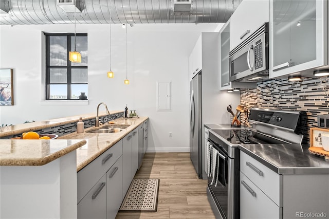3100 Huron St Unit 1A, Denver, CO 80202 - kitchen with stainless steel appliances, stainless steel countertops, decorative backsplash, a peninsula, and glass insert cabinets