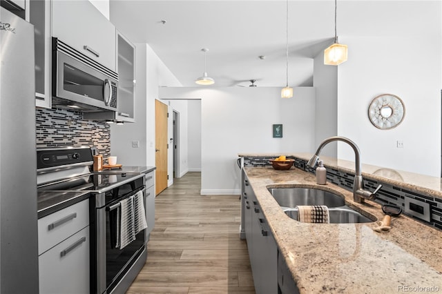 3100 Huron St Unit 1A, Denver, CO 80202 - kitchen with stainless steel appliances, decorative backsplash, hanging light fixtures, light wood-style floors, and light stone counters