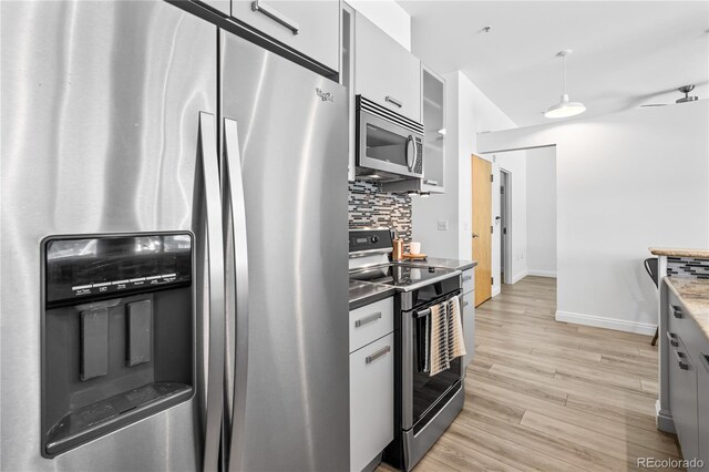 3100 Huron St Unit 1A, Denver, CO 80202 - kitchen featuring appliances with stainless steel finishes, tasteful backsplash, light wood-style floors, pendant lighting, and white cabinets