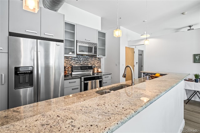 3100 Huron St Unit 1A, Denver, CO 80202 - kitchen featuring appliances with stainless steel finishes, decorative backsplash, wood finished floors, pendant lighting, and glass insert cabinets