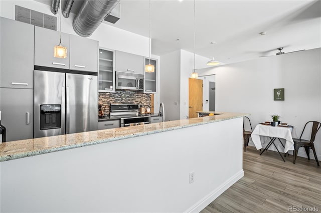 3100 Huron St Unit 1A, Denver, CO 80202 - kitchen featuring appliances with stainless steel finishes, tasteful backsplash, wood finished floors, glass insert cabinets, and decorative light fixtures