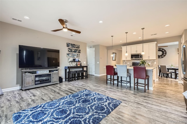 10555 Boston St, Commerce City, CO 80640 - living room featuring a ceiling fan, light wood finished floors, baseboards, and recessed lighting