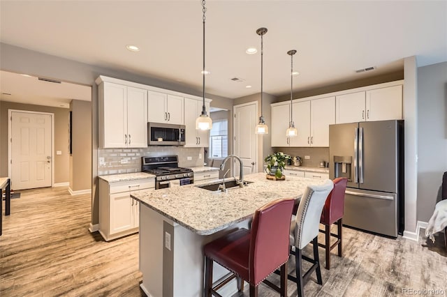 10555 Boston St, Commerce City, CO 80640 - kitchen with stainless steel appliances, a sink, light wood finished floors, tasteful backsplash, and baseboards