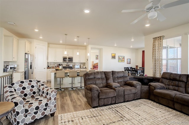 living room featuring ceiling fan, light wood-type flooring, and recessed lighting