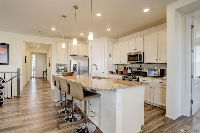 kitchen featuring light wood finished floors, a toaster, a breakfast bar area, appliances with stainless steel finishes, and a sink